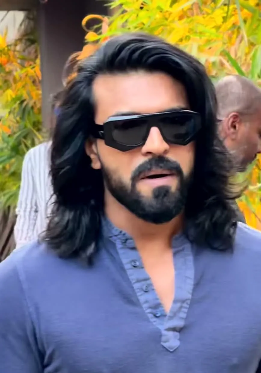 Ram Charan — Close on the neckline — no collar and no stand, a deep V half-placket, four tonal buttons all undone, and the gathered inner edge of the placket band
