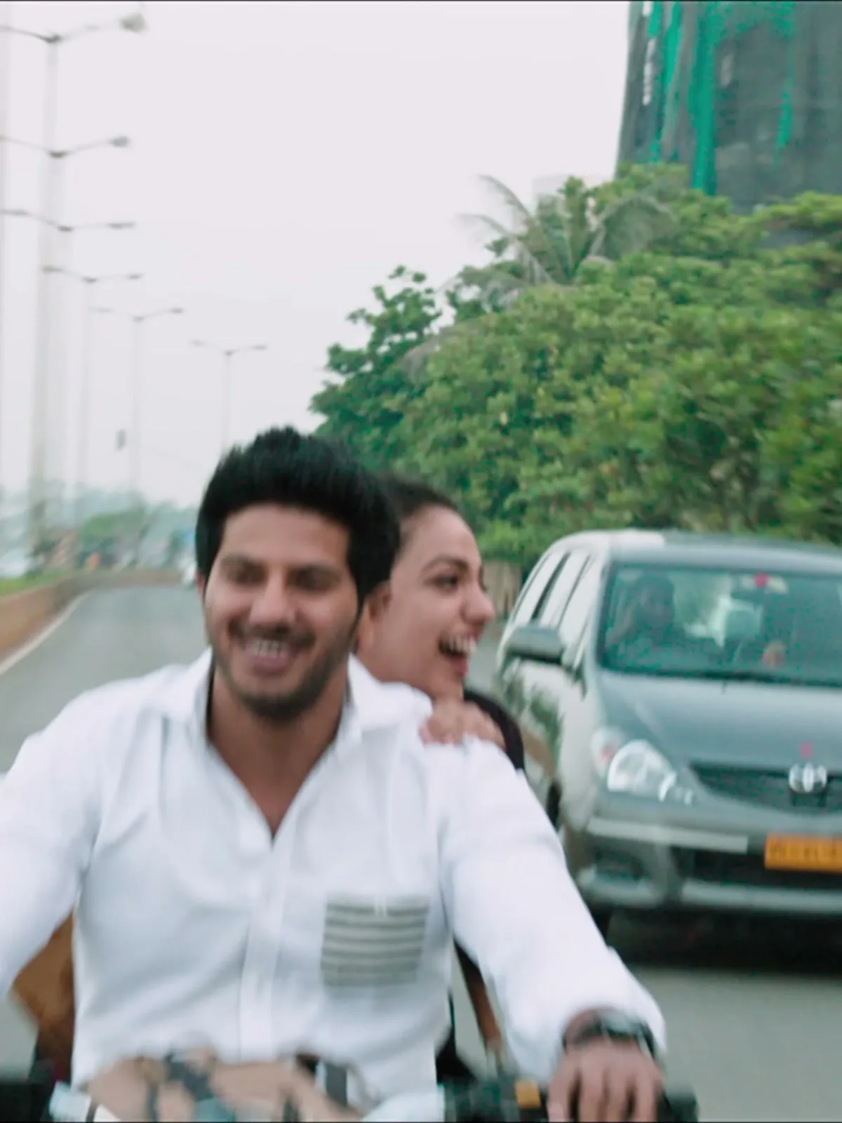 Dulquer Salmaan — On the bike: the striped chest pocket against the plain white body