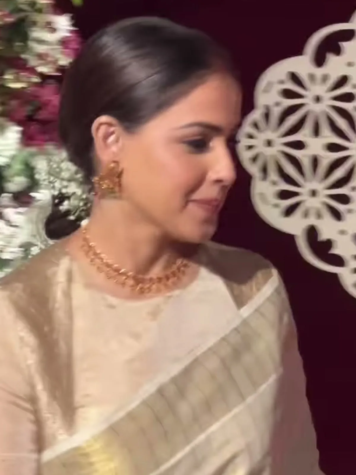 Genelia D’Souza — In profile — the round-necked, full-sleeve tissue blouse and the long gold drop earring that is described but not listed