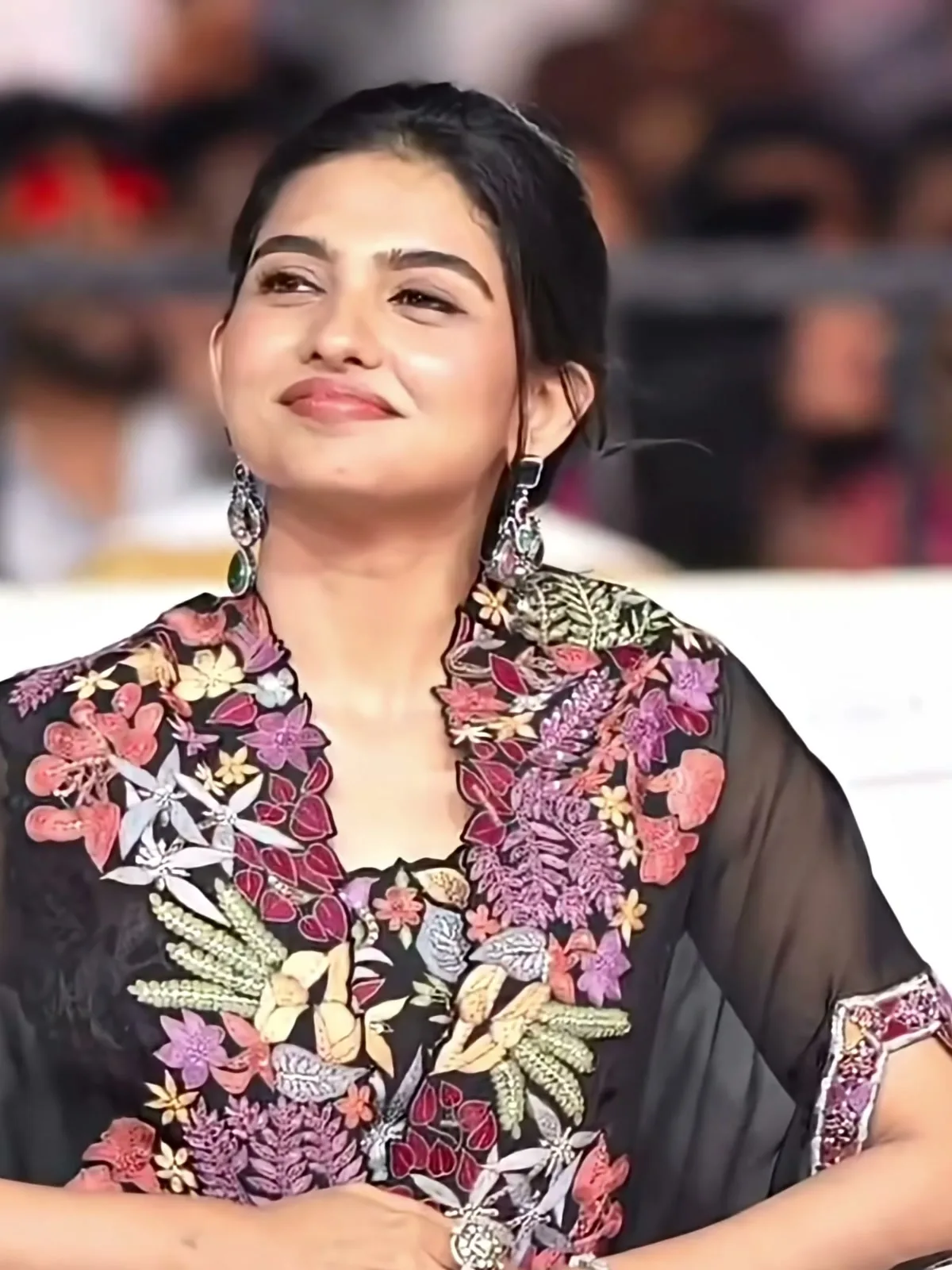 Mamitha Baiju — Seated, cape spread — the appliqué floral bands run the full length of both front edges