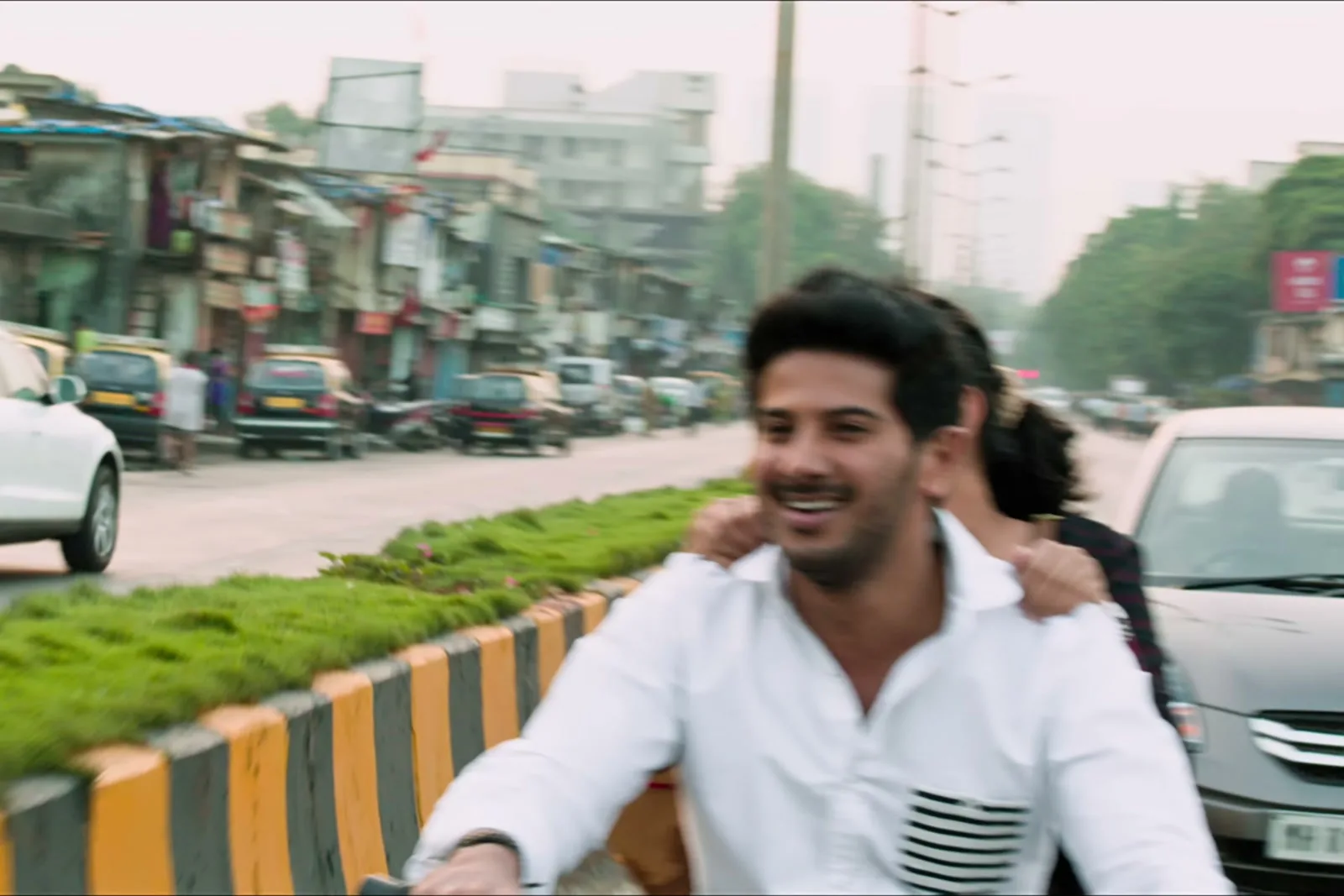Dulquer Salmaan — Riding through traffic — the pocket reading as a block of pattern at distance