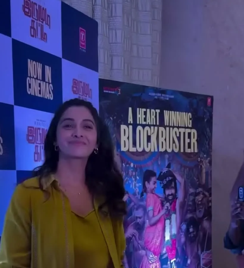 Priya Bhavani Shankar — The step-and-repeat that dates the look: the film's Tamil title, "NOW IN CINEMAS", and the blockbuster standee beside her