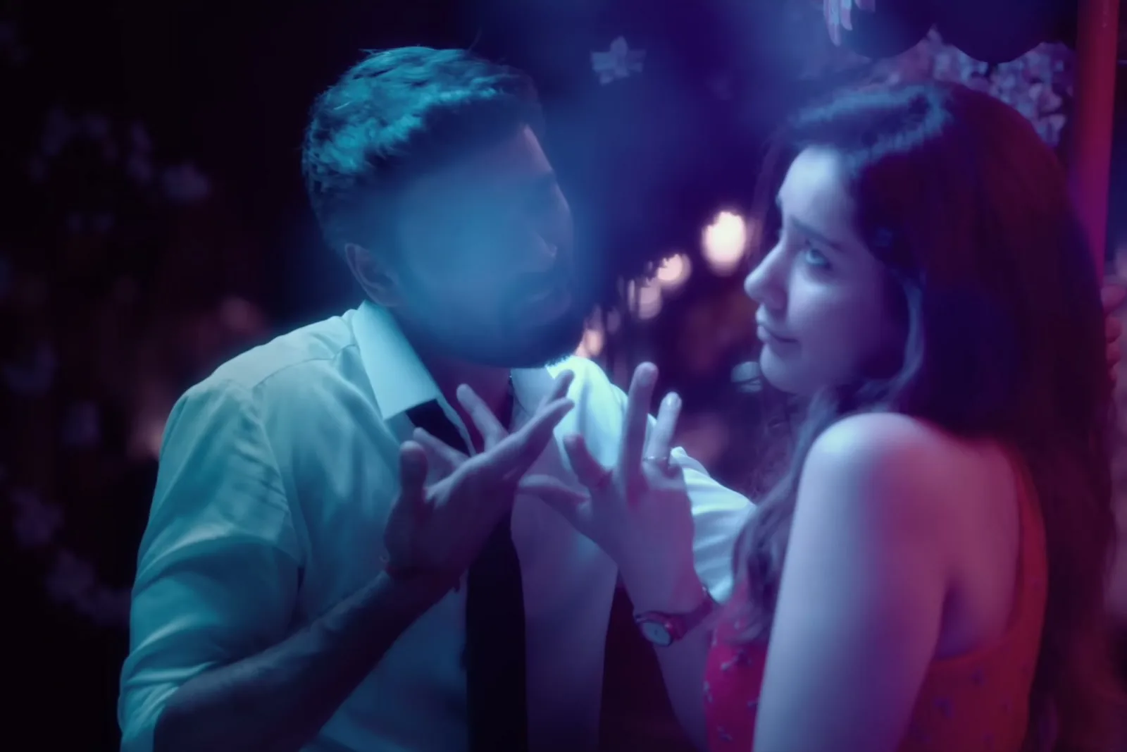 Dhanush — Mid-song, close: the sleeve rolled back to just below the elbow