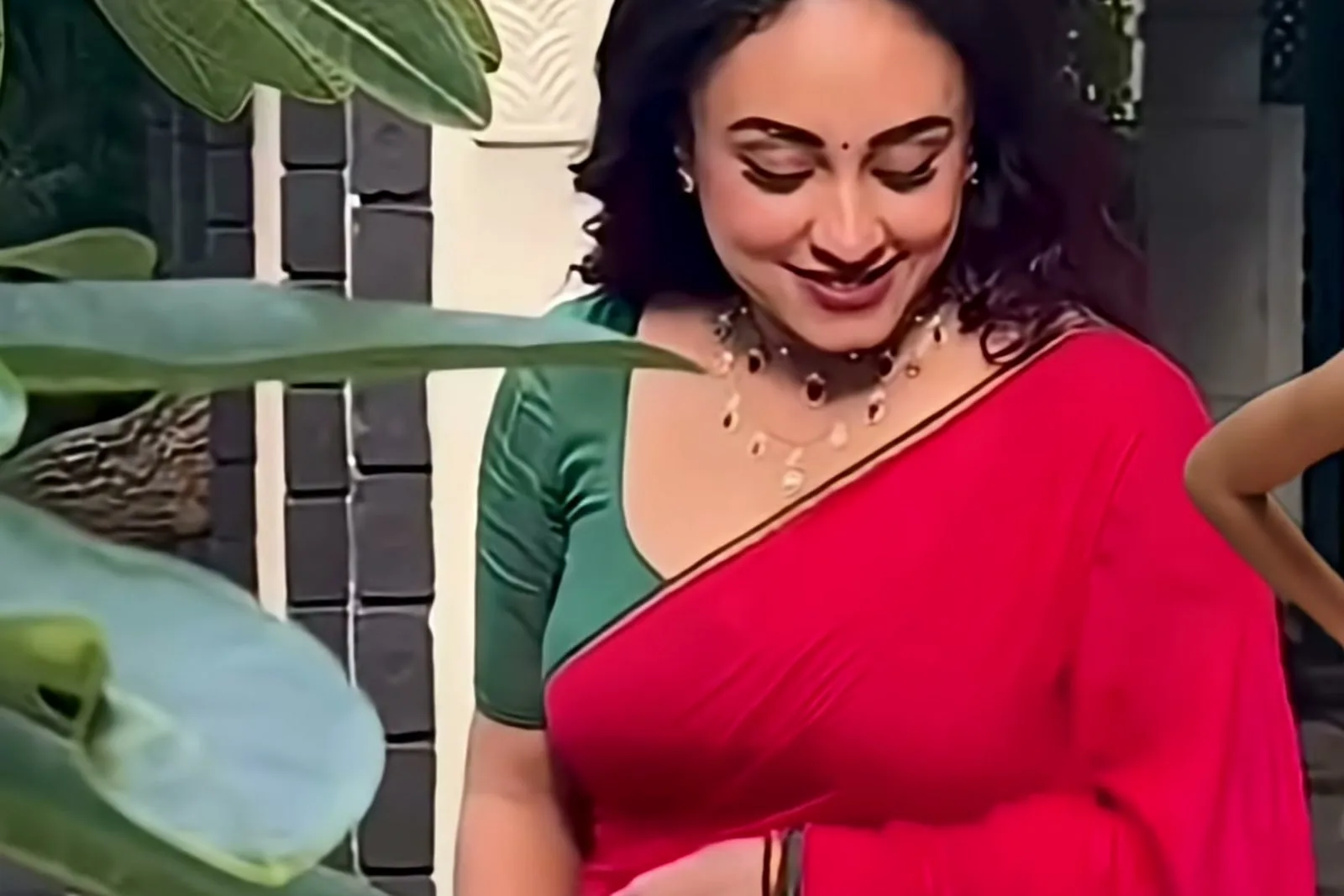 Pearle Maaney — Outside, mid-turn — the pallu over the shoulder and the green blouse against the red