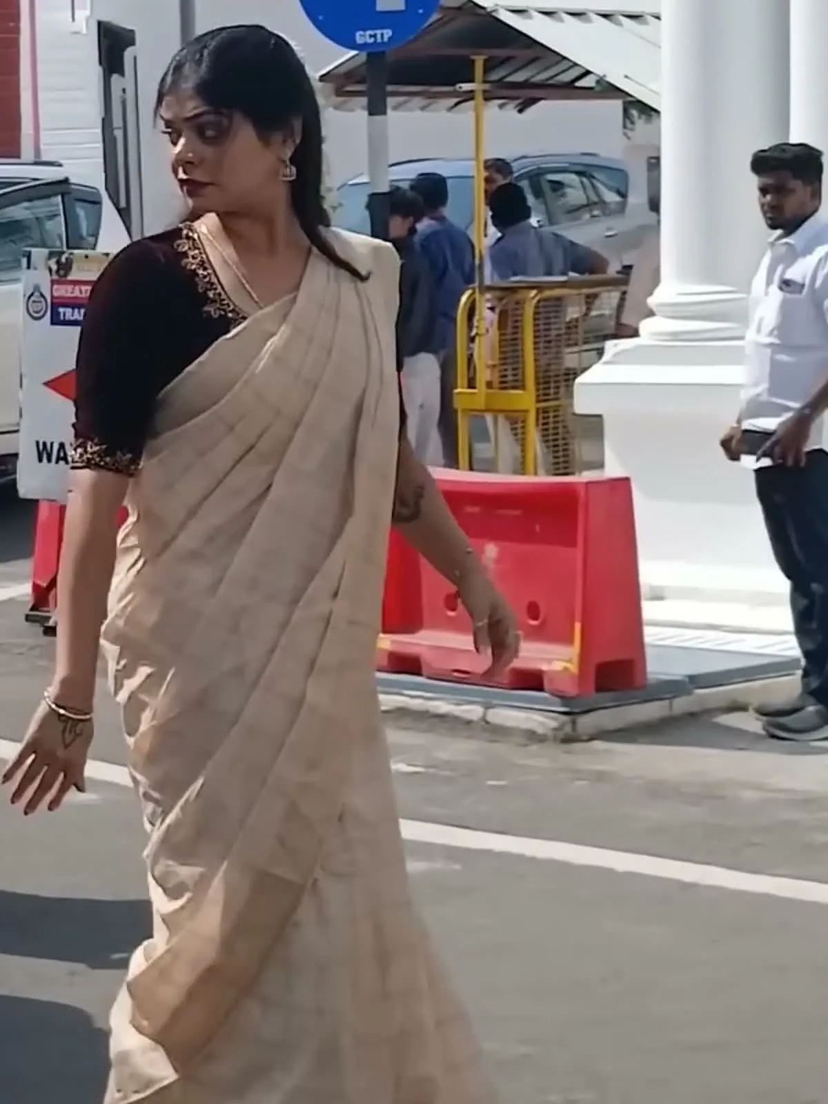 Kanimozhi Santhosh — Mid-stride: how plainly the saree is draped, and how little there is on it