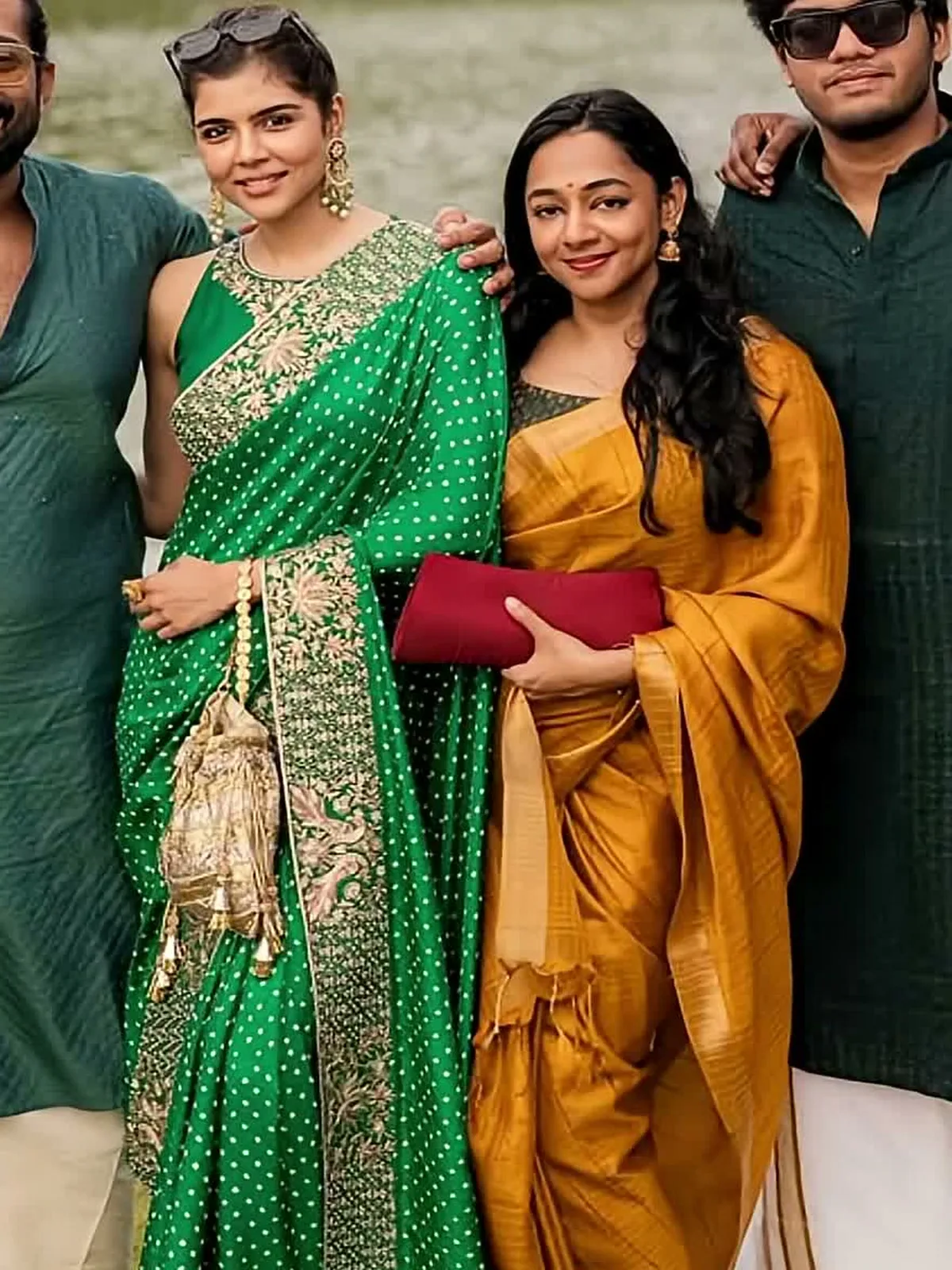 Kalyani Priyadarshan — Full length by the lake — the broad peacock-and-lotus border down the pleats, potli in hand