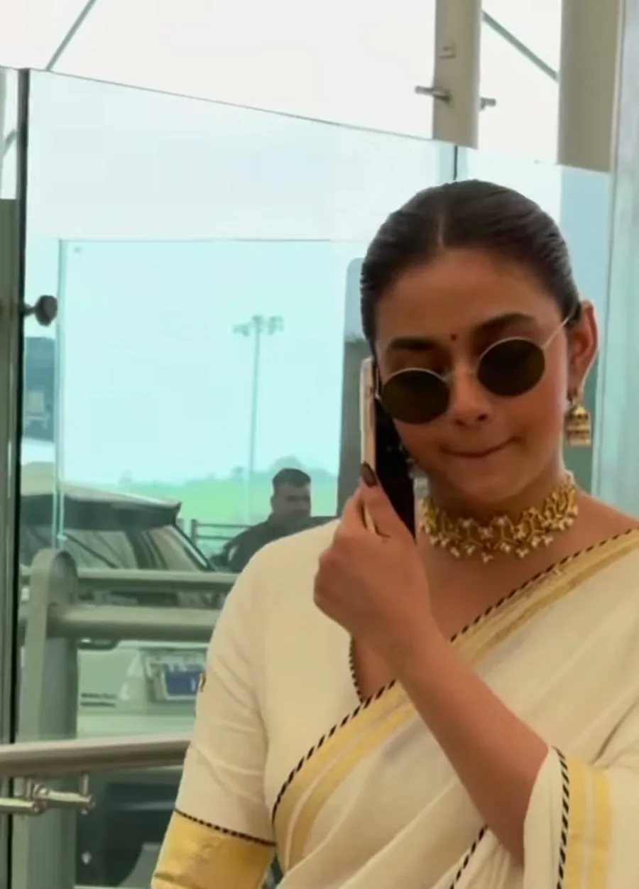 Keerthy Suresh — Phone to her ear — the black-and-white piping and the gold cuff on the blouse