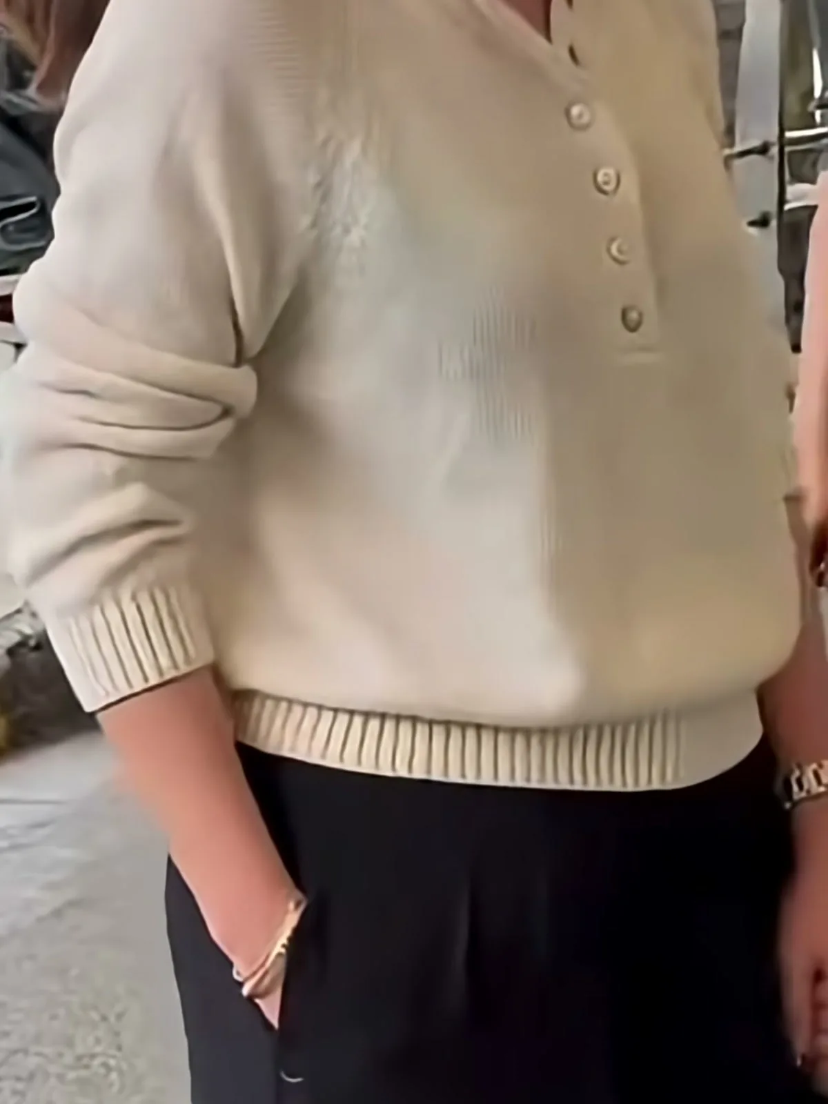 Nayanthara — Close in — five small tonal buttons, the ribbed cuff, and the deep ribbed hem band over the pleated waist