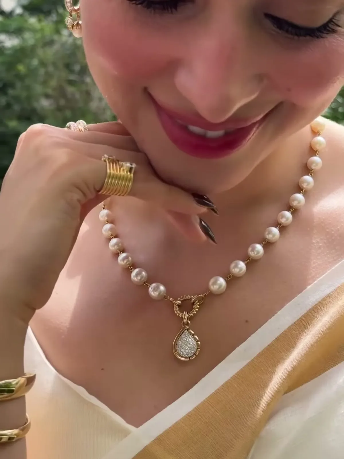 Tamannaah Bhatia — Close in on the necklace — pearls linked by gold connectors, the twisted rope circle at the centre, and the split-bezel pear pendant hanging off it