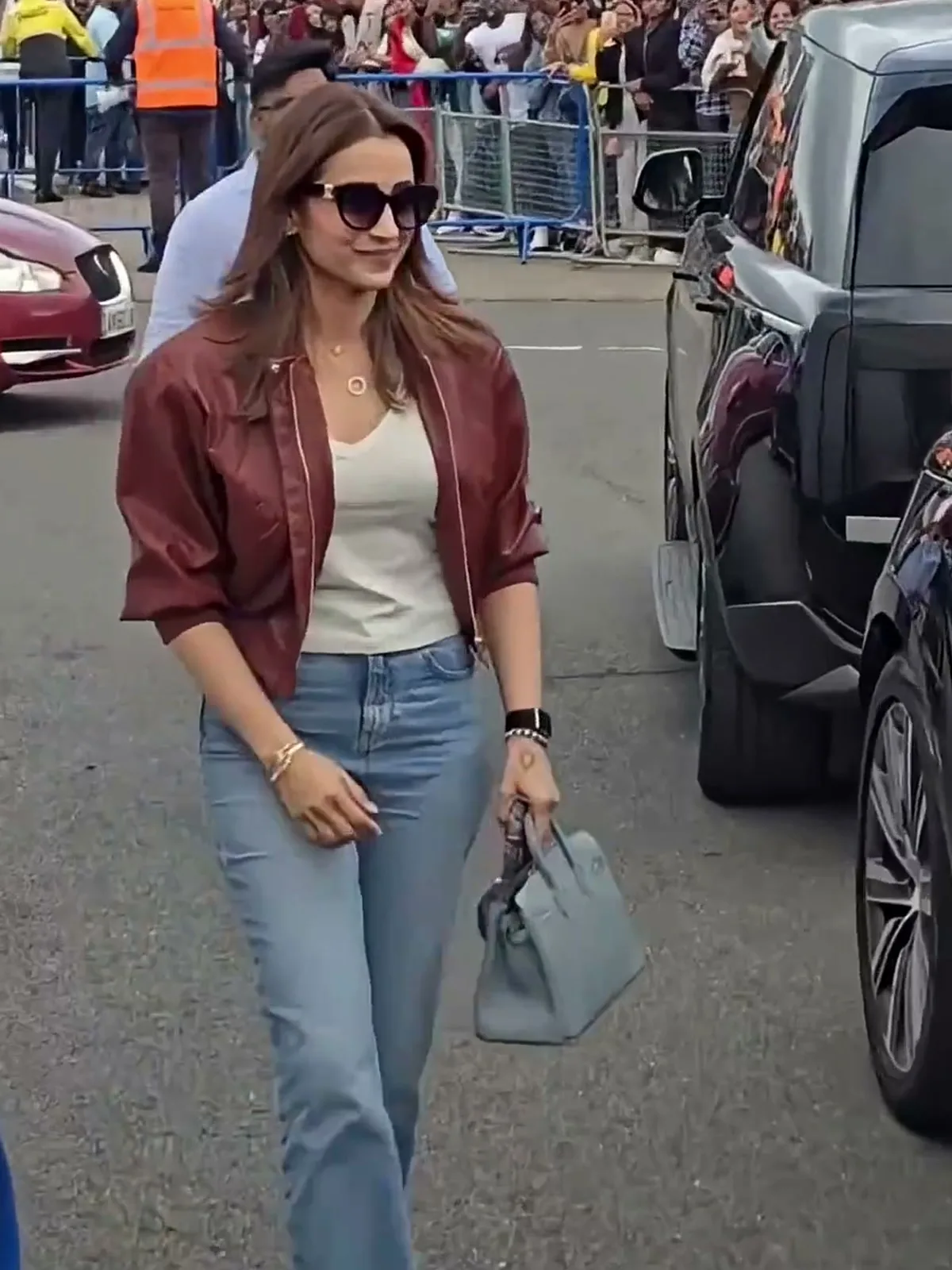 Trisha Krishnan — The whole fit, full length: cropped bomber, tucked ribbed tee, light straight jeans, gold flat sandals