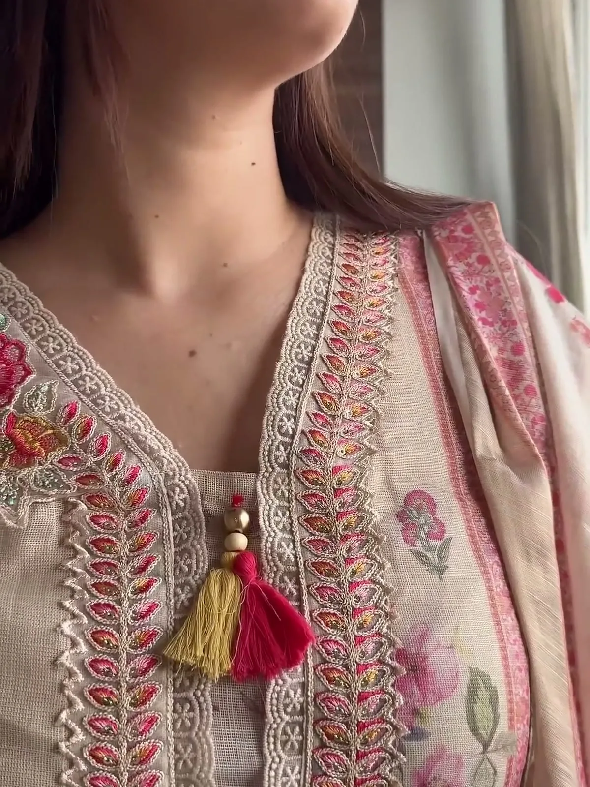 Manika Dhingra — Close on the V-neck: embroidered leaves, scalloped lace edging and the tassel ties
