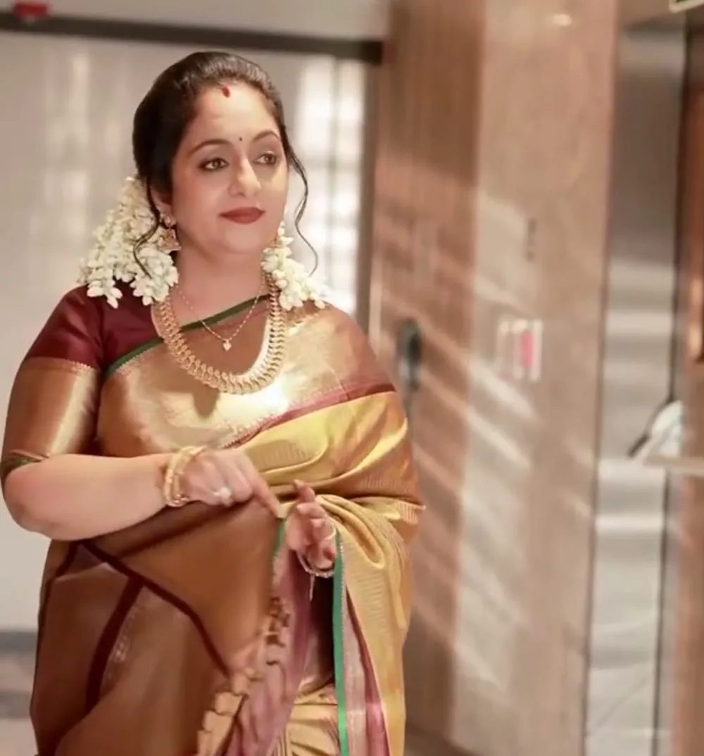 Sindhu Krishna — In the hotel corridor — the same saree, coppery under warm light